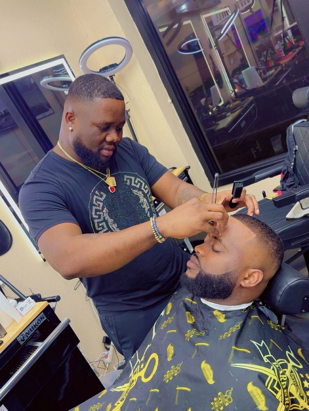 Barber shaping a client’s eyebrows with a razor